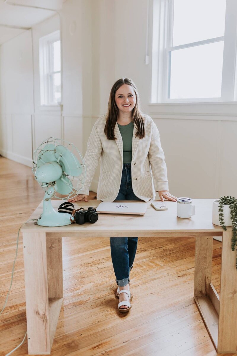 McKenna Fahrenbruch, digital marketing strategist at Graceful Exposure Media, standing at her modern home office desk, planning social media content and video marketing strategies for small businesses."