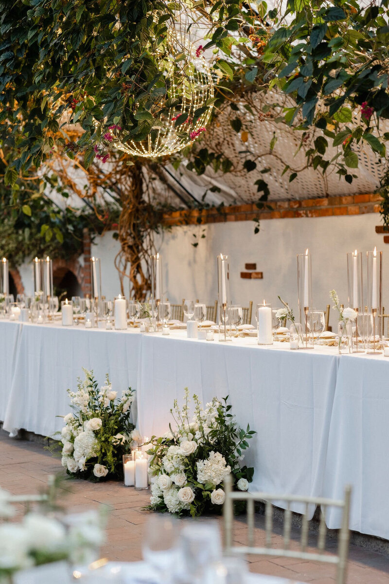 wedding set up at at Madison Greenhouse in Newmarket, white linens and lots of candles, white flowers