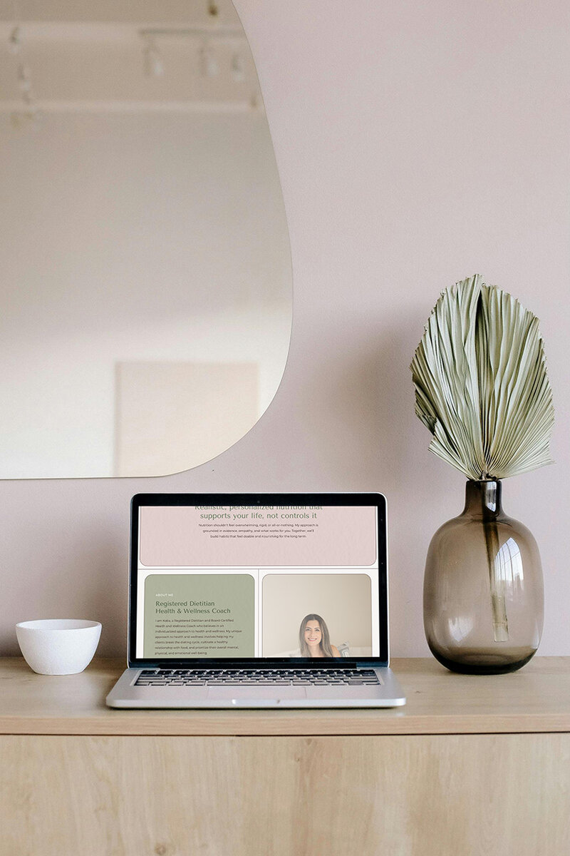 Laptop on a desk with a pink wall behind, showcasing a vibrant workspace for a Showit website design.