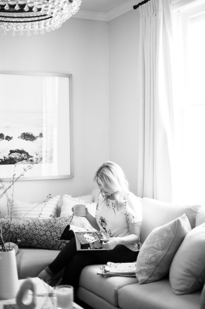 a woman reading a magazine while sipping tea in a casual elegant living room with lots of light