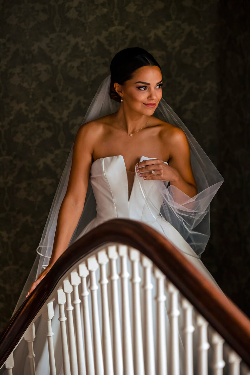 A bride looks out the window while on a staircase at her Ohio home before the wedding.