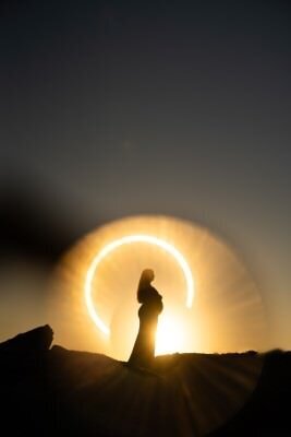 Silhouette of pregnant woman against golden circular light during maternity photo session by St Augustine family photographer