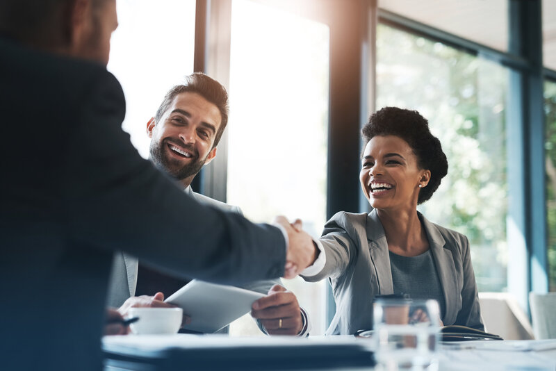 A group of three co-workers meeting each other and shaking hands.