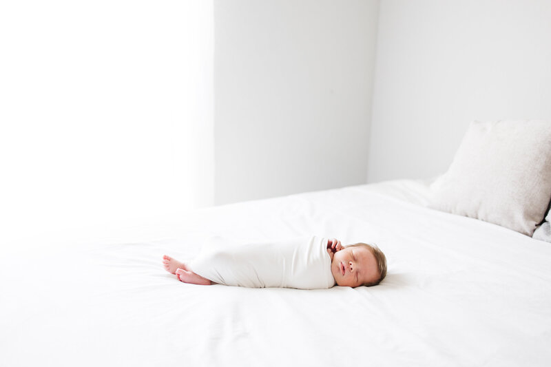 Photo of young baby and his mother laying down on a blanket in a field taken by Meg Staheli Photo, a family photographer in College Station.