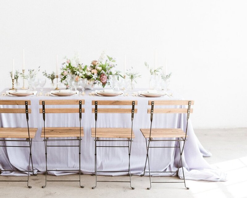 Tablescape photograph with lavender linen and wooden chairs in California