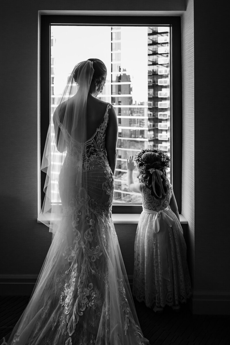 Bride and flower girl look out hotel window in Chicago