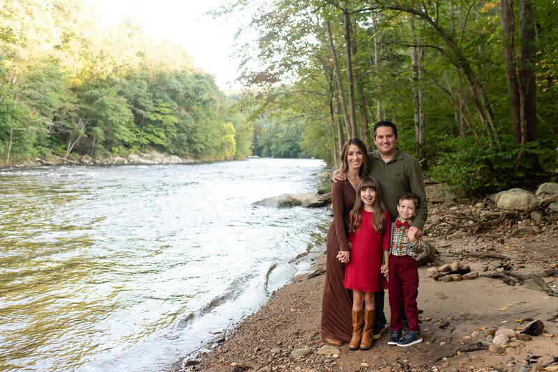 Family of four smiling at the camera by the river