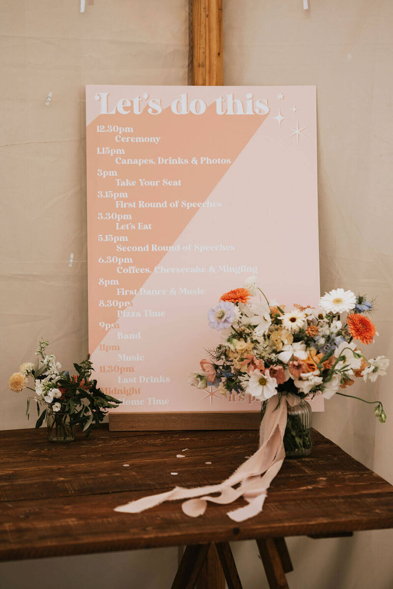 Order of the day sign at Broadfield Court with the bridal bouquet