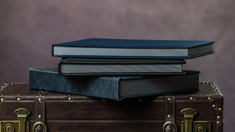 A stack of beautifully restored modern wedding albums, showcasing updated designs and craftsmanship.