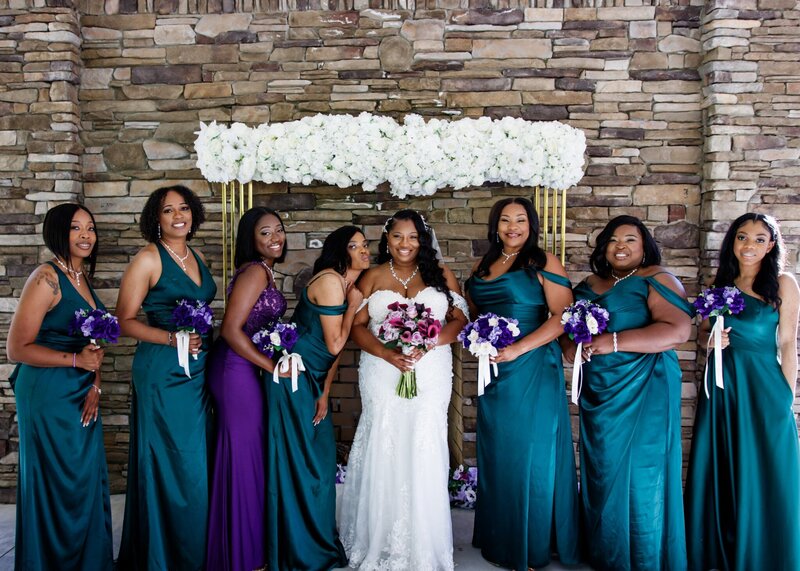 a bridal party in teal and purple pose in front of the ceremony space