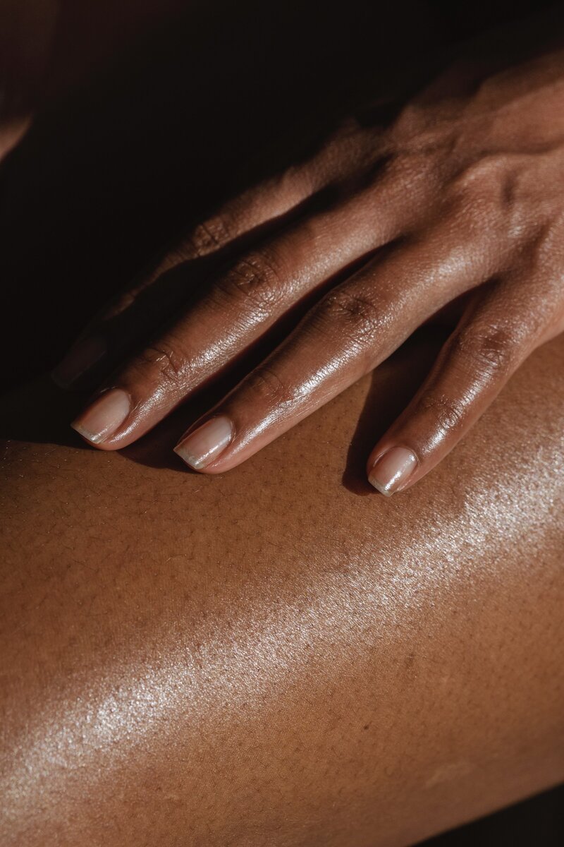 dark skinned woman hand with manicured nails and glowing skin