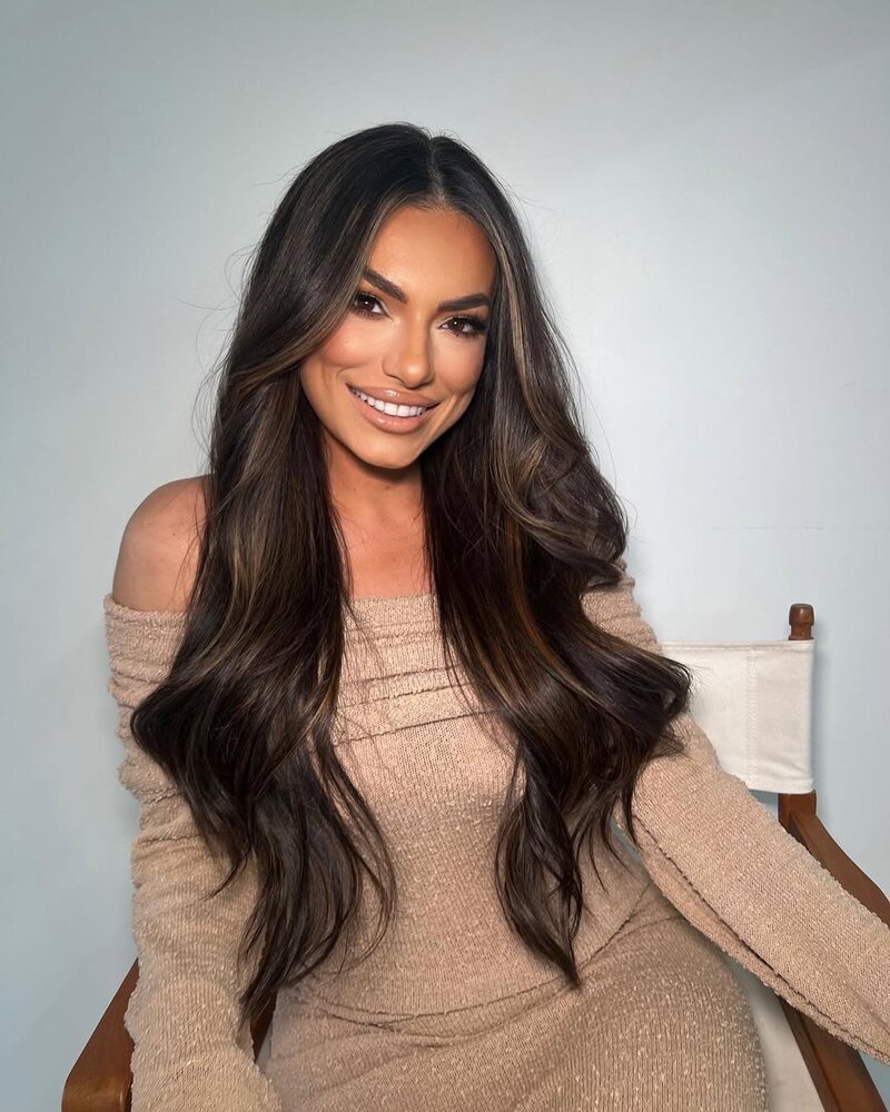 Woman leaning back in a chair smiling with her legs crossed.
