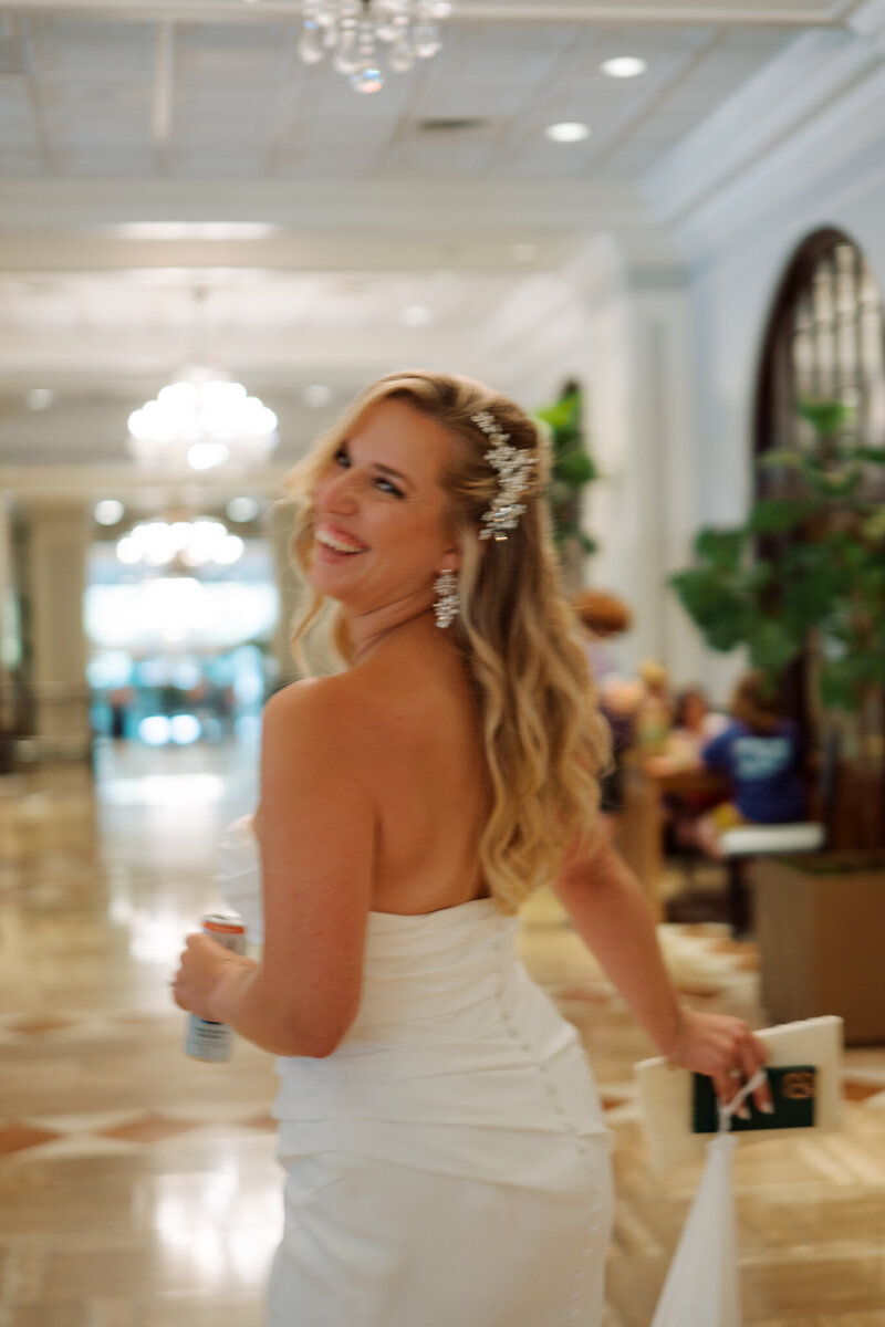 Bride smiling and walking through a brightly lit elegant venue.