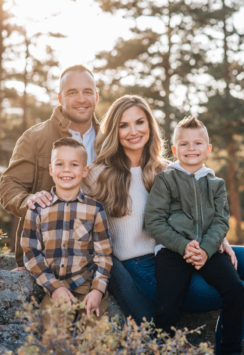 denver family photographers captures small family sitting together on a rock in their outdoor family photos denver in the woods with young children