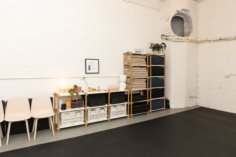 Held Space studio amenities pictured: yoga blankets, props and more organized in wooden shelves.