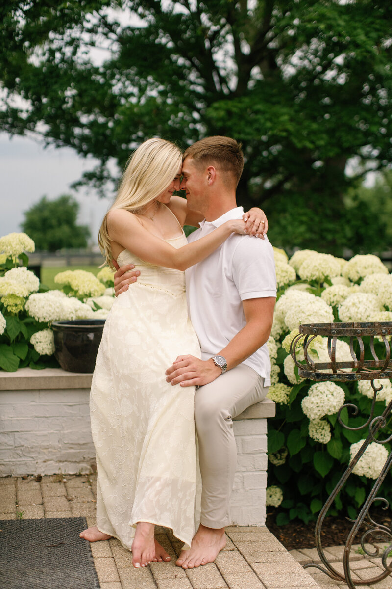 A wedding couple embraces on a tropical rooftop terrace with modern buildings and palm trees in the background.