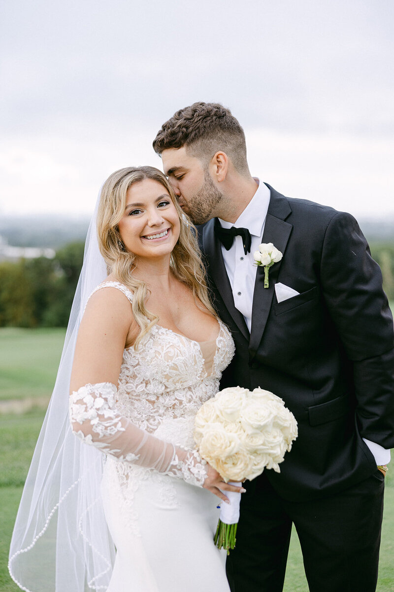 a groom kissing his bride on the head