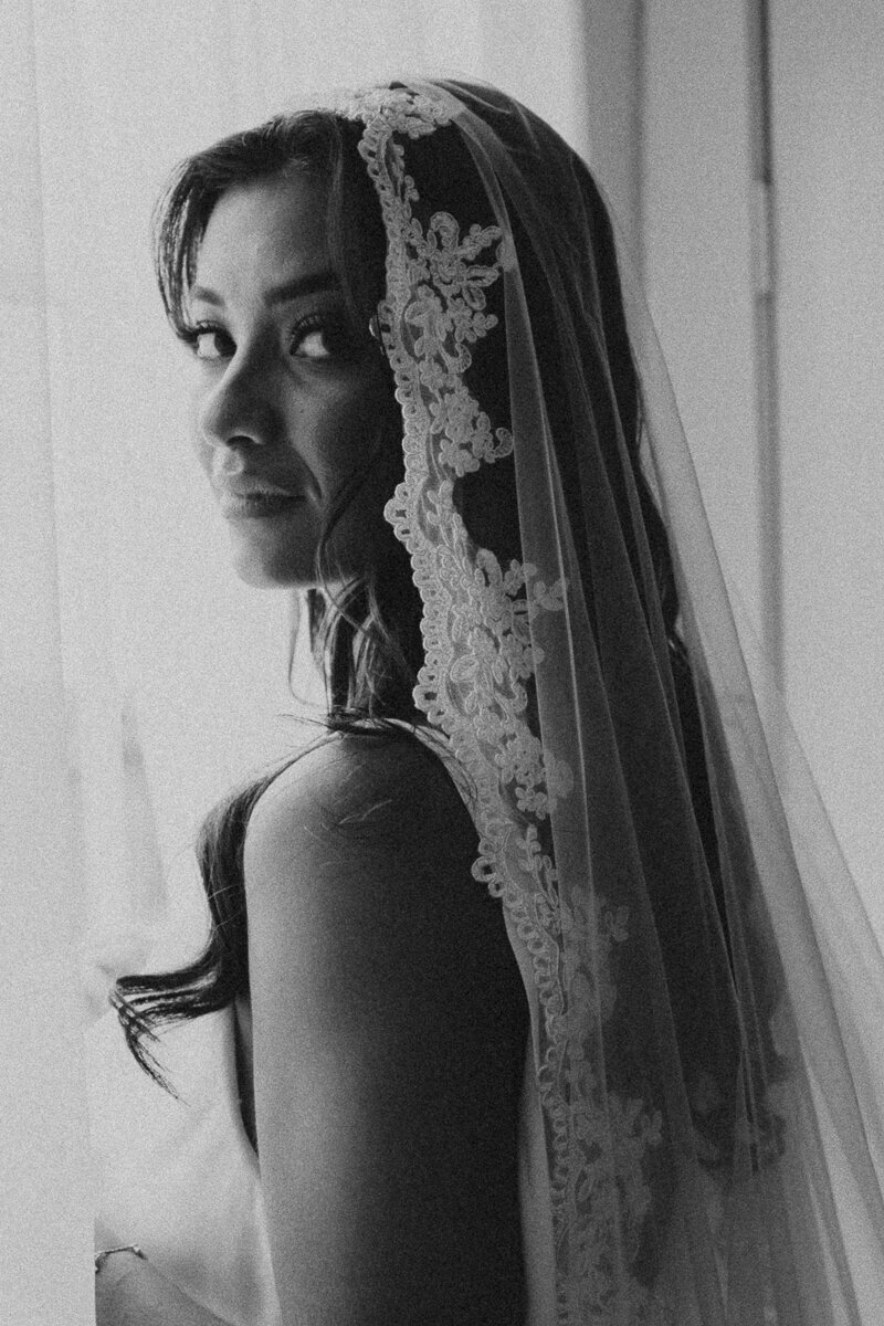 bride looking out window in a lace veil in pensacola florida