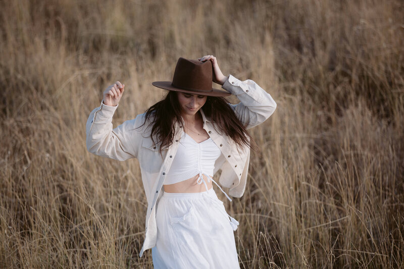 woman walking through a wheat field in a cowboy hat