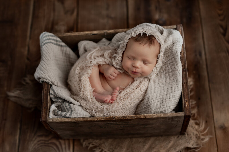 baby wrapped and in crate at photo session