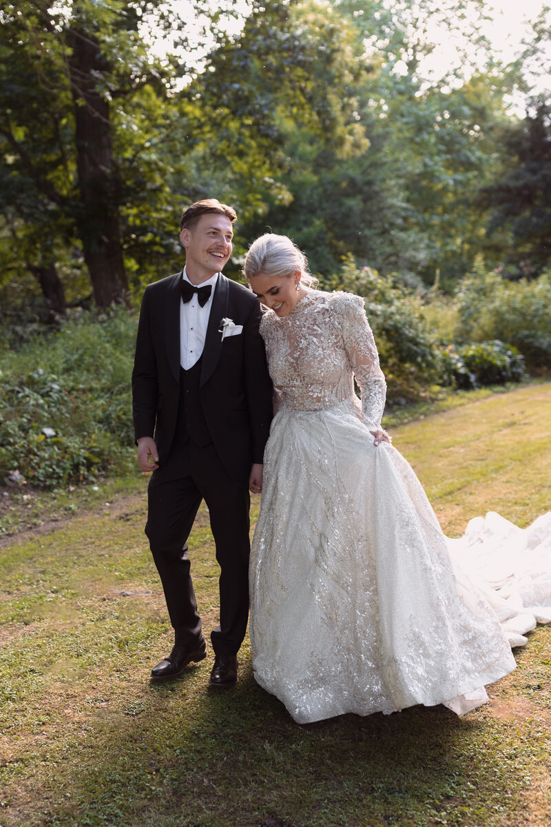 A couple walk hand in hand on the lawn of their destination wedding venue chateau du queille south of france