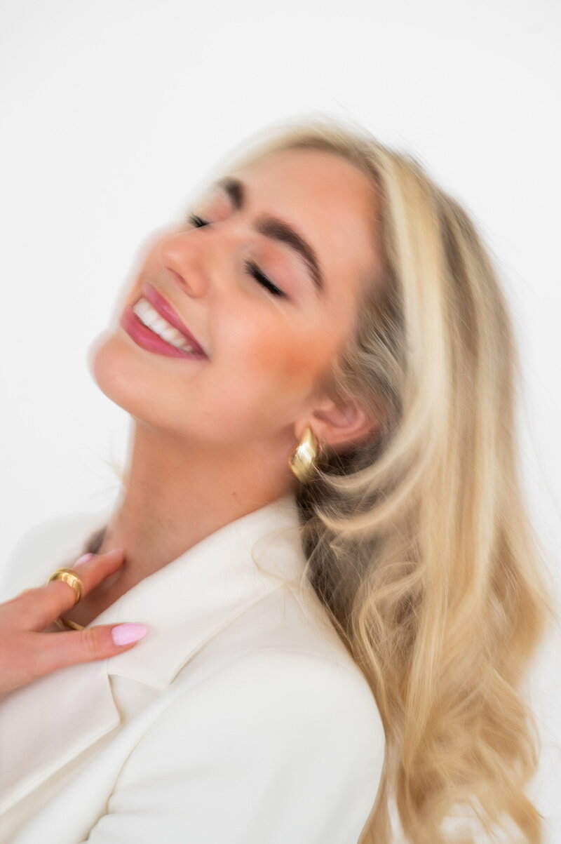 Close-up of Amelia Waters smiling in white blazer, capturing the warmth and personality behind Sunday Social Collective