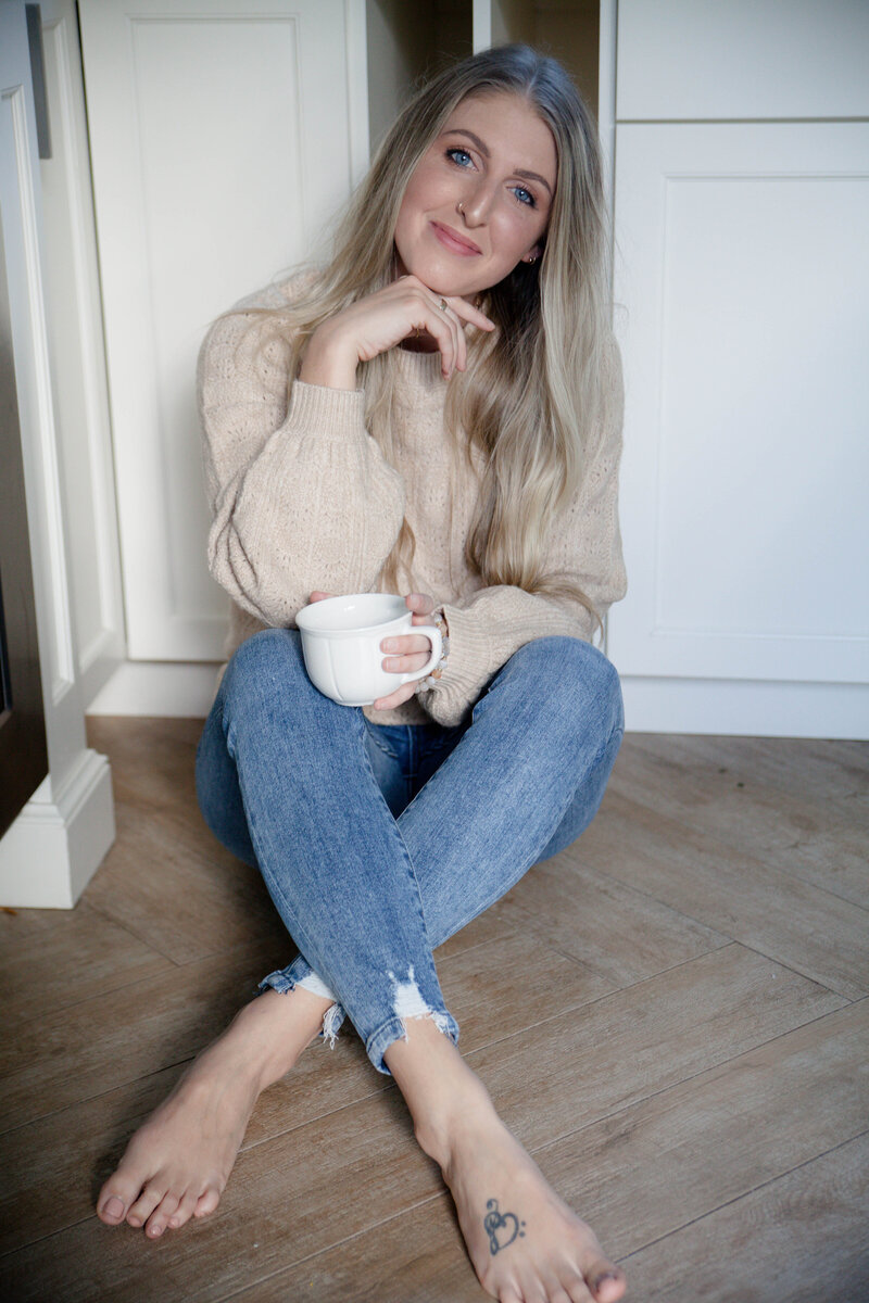 Business owner sitting on the floor with a coffee cup in her hand.