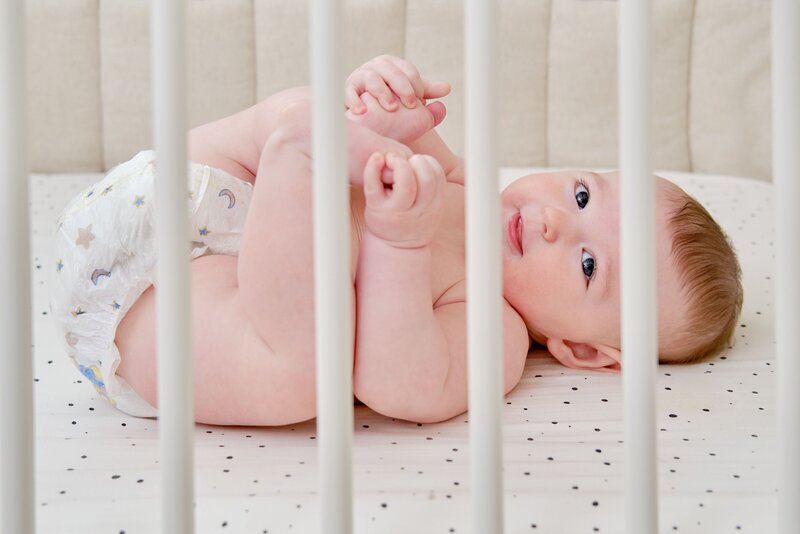 baby laying in a crib smiling