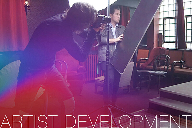 Artist Development Program Promotional Image Mark lookings through camera assistant holding reflector beside him