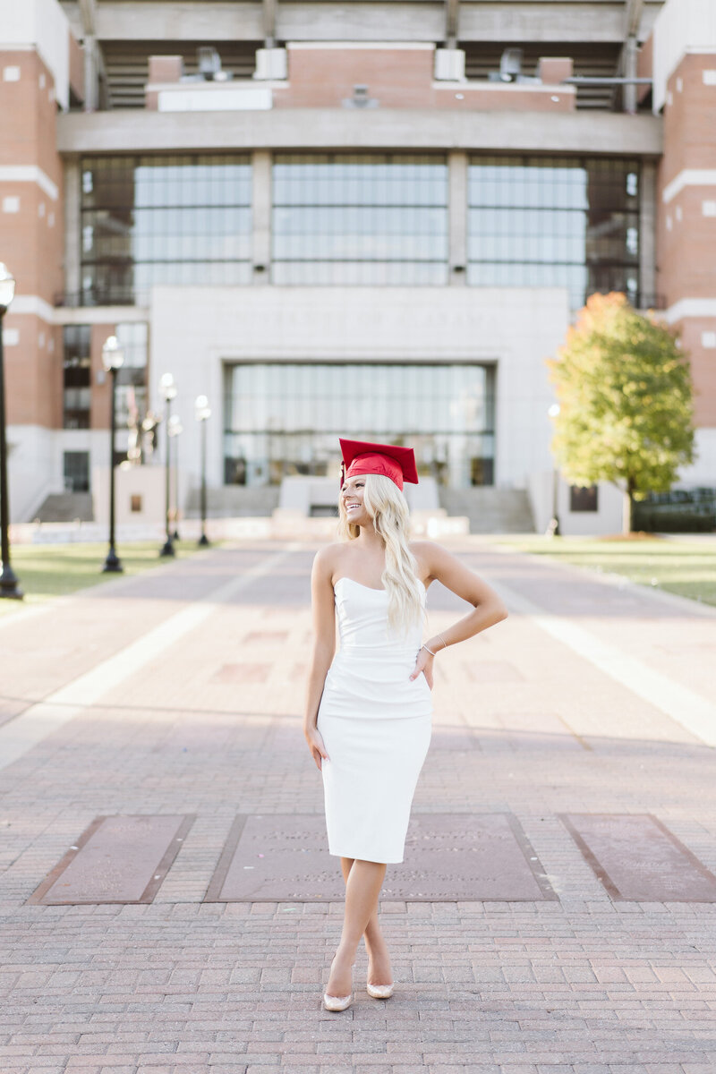 a graduate of the university of alabama with a red cap on standing in front of Bryant Denny Stadium