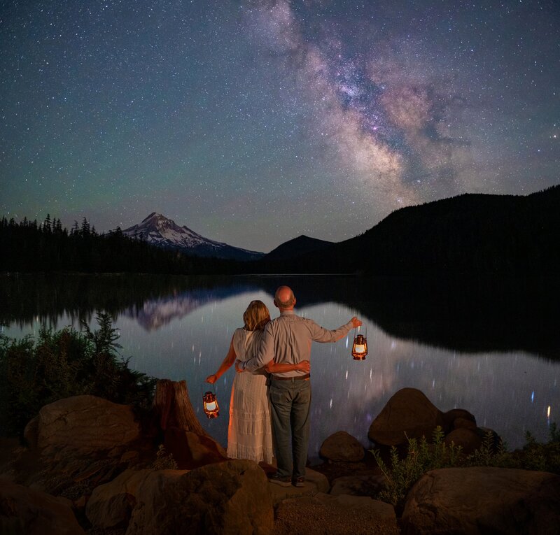 A couple explores the mountains in their wedding attire at night with lanterns