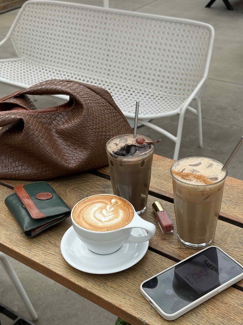 3 cups of coffee, a phone, and a wallet on top of a table