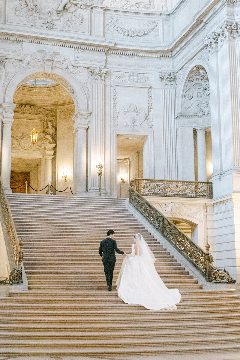 Fairytale couple walking up the steps of the grand staircase in the San Francisco city hall