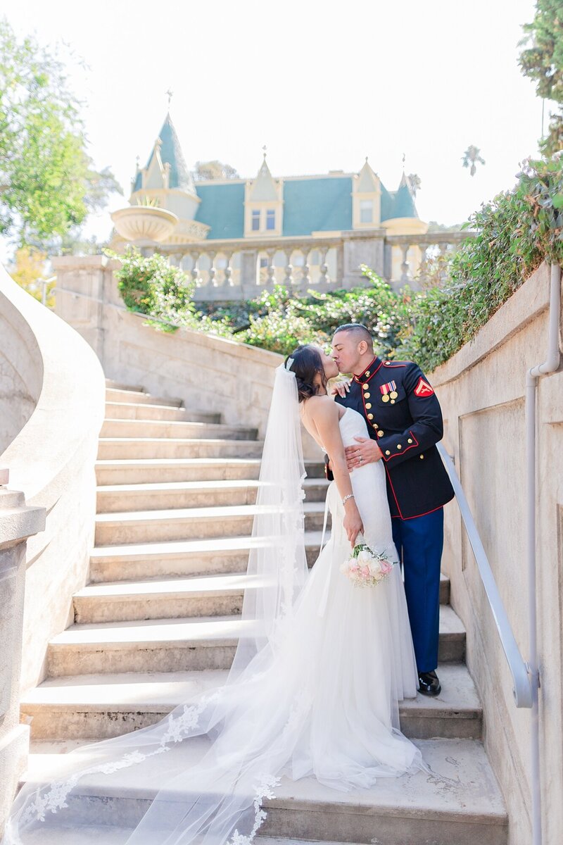 bride and groom kiss on a staircase of a fairytale castle