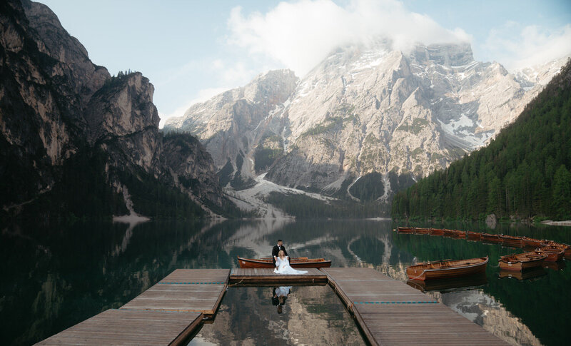 Couple sits in the middle of the Lago di braies boat dock for an amazing Dolomites Elopement Photo 