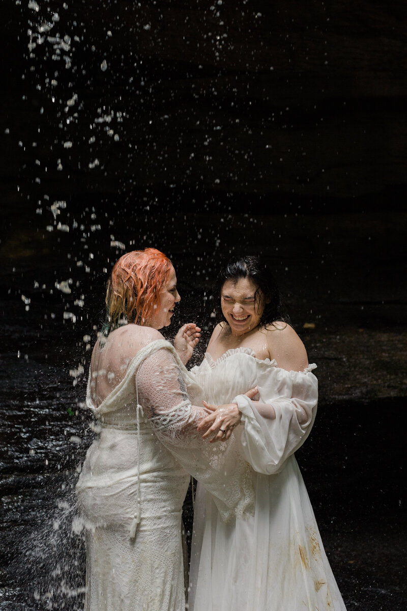Lesbian couple having fun under Kentucky's waterfall