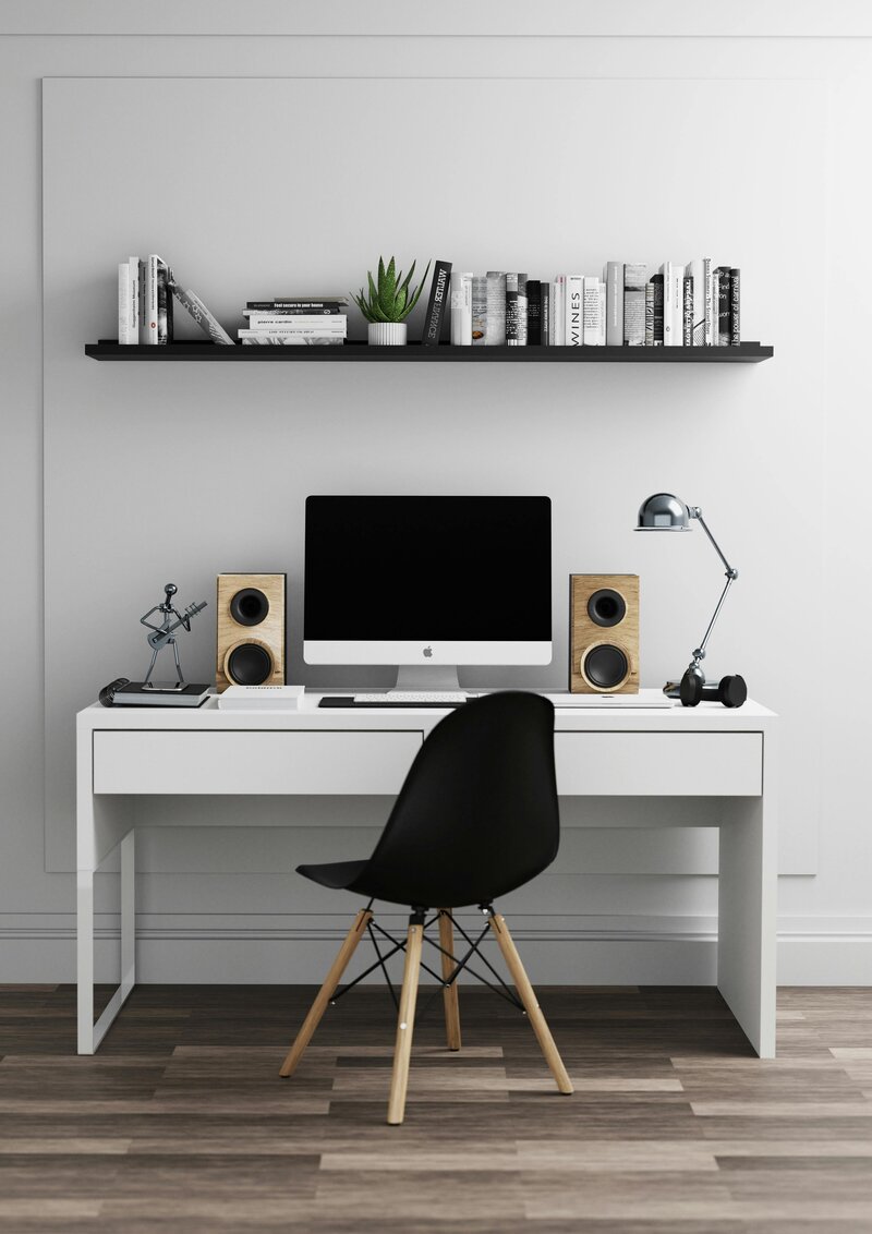 Minimal and clean desk featuring books, plant, speakers, a lap, and a Mac desktop