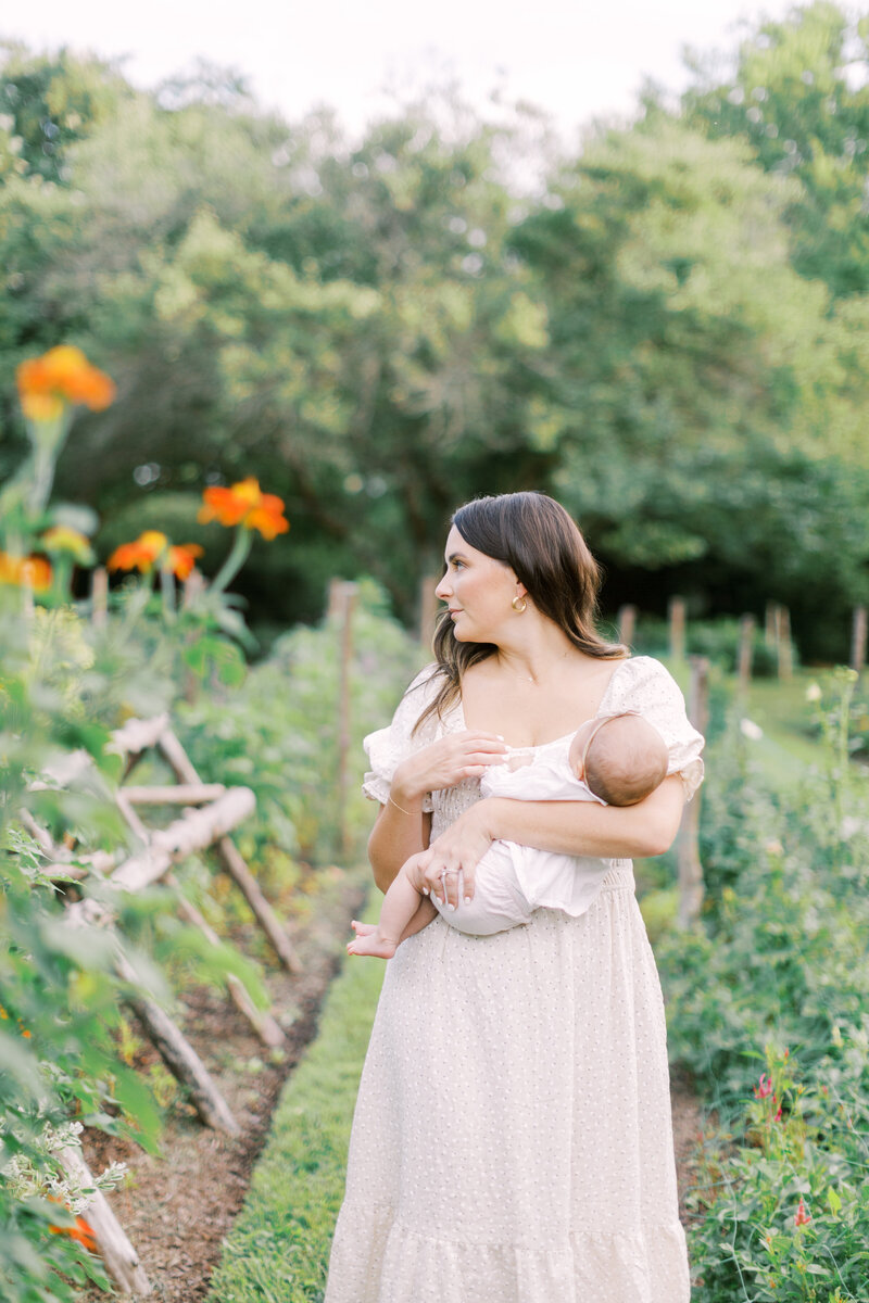 Mother holding her newborn in a flower garden