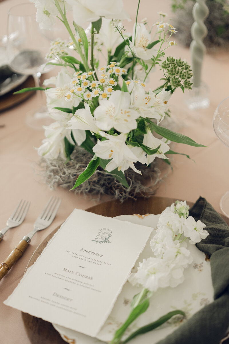 photo of a luxury wedding tablescape with forks plates florals and menu card