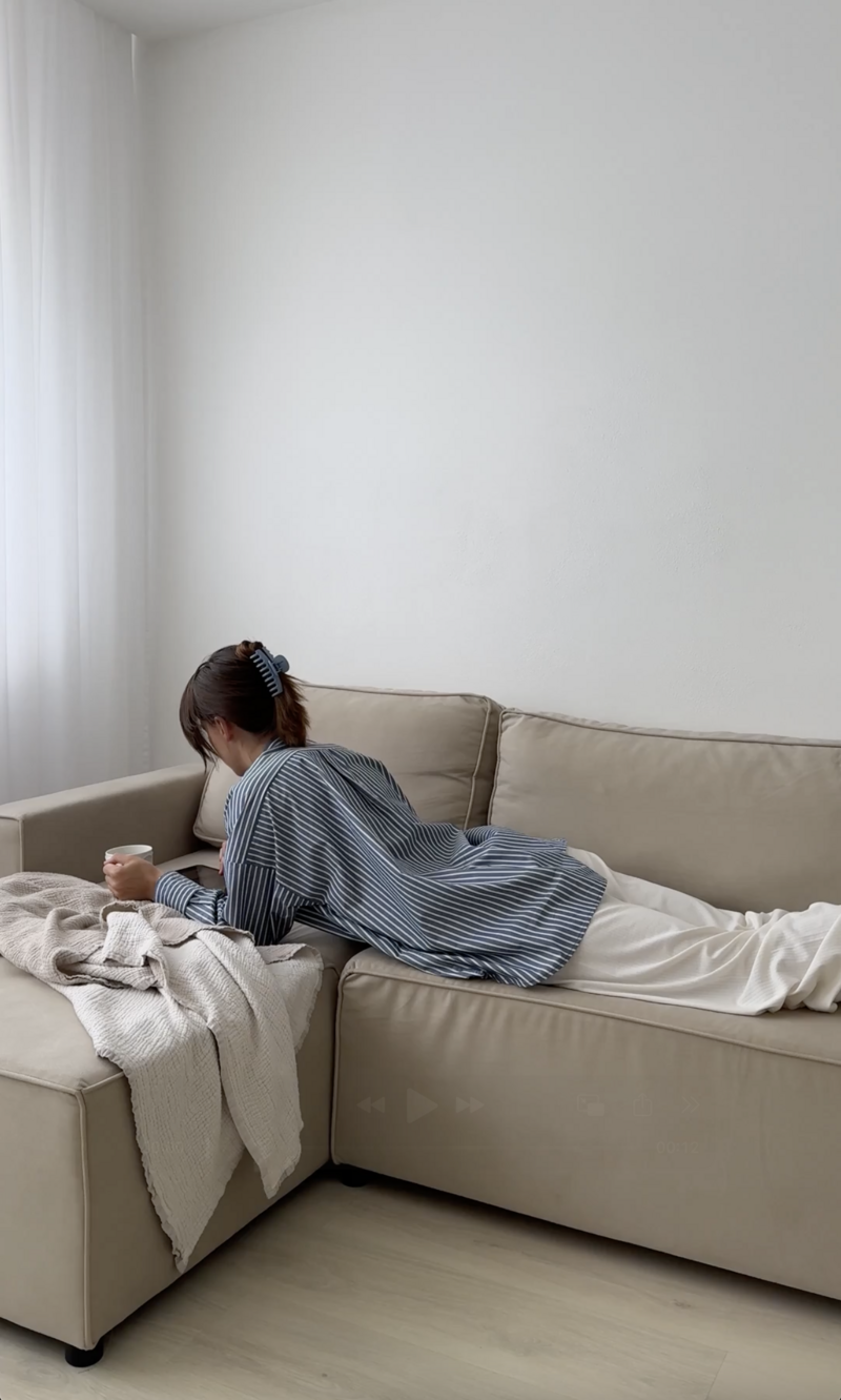 A healthy, stylish girl planning her goals and daily routine with a digital Notion productivity template on sofa with a coffee in hand
