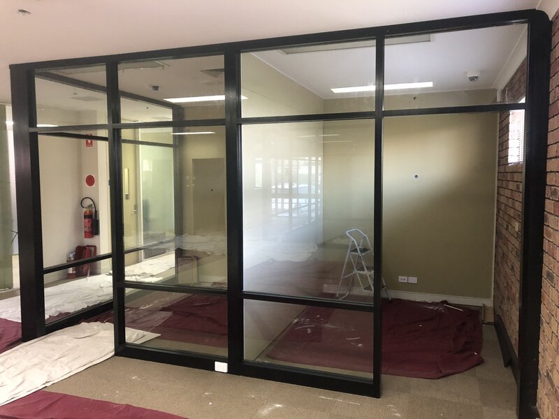 Office space featuring glass doors and partitions, offering a modern and organized layout.