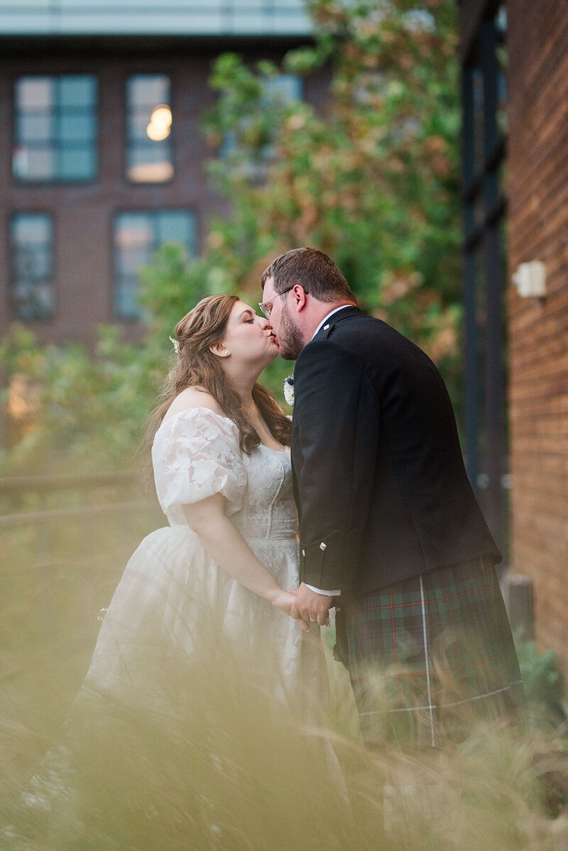 jewish bride kissing and holding hands with scottish groom on the side terrace at District Winery in DC 