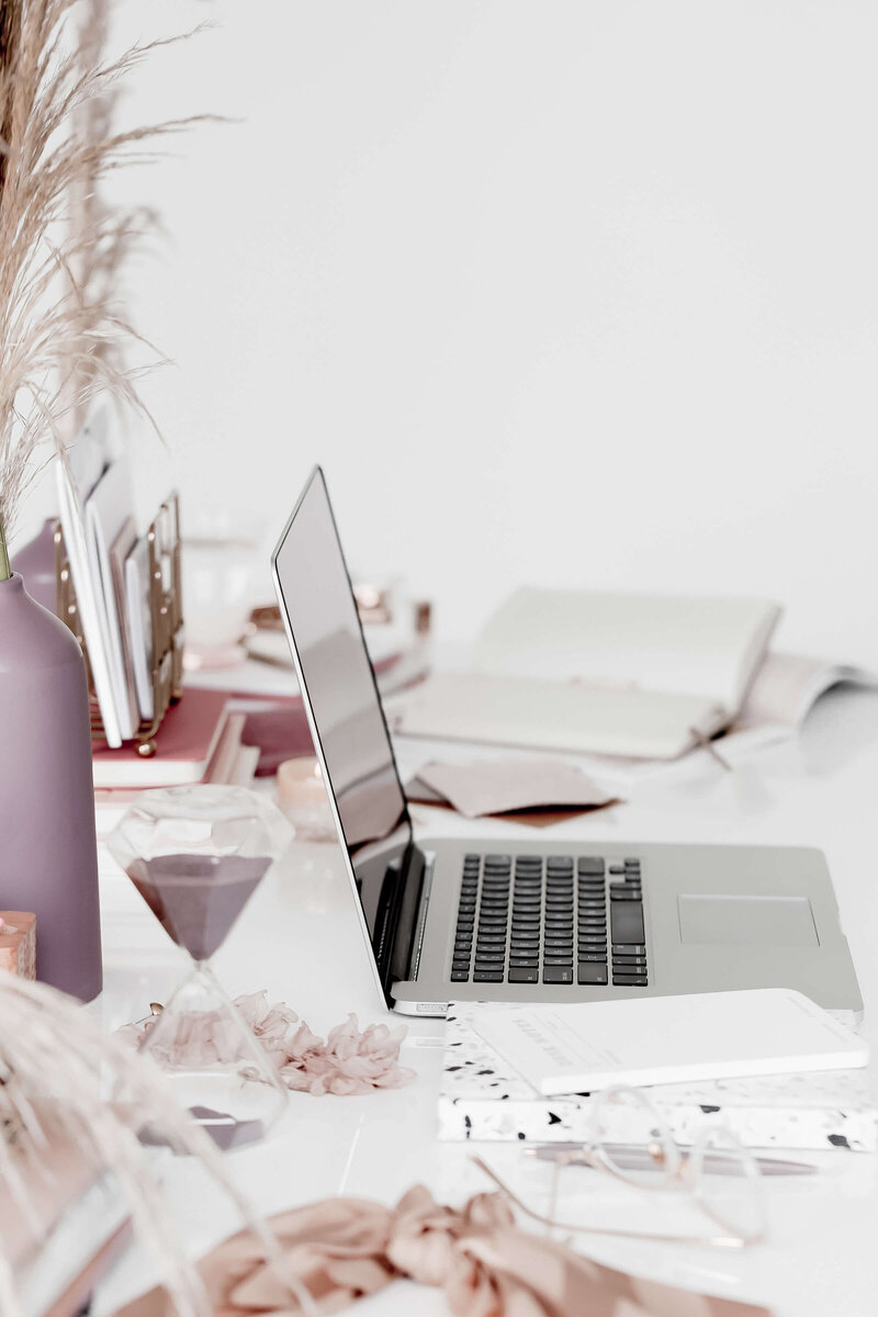 Minimal styled workspace with laptop, notebook, and coffee cup on a clean desk, representing organized HoneyBook systems for wedding photographers.