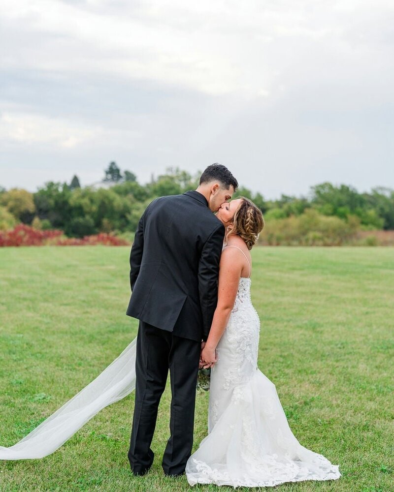 A bride and groom walking up the grand steps of a majestic building, holding hands and smiling at each other.