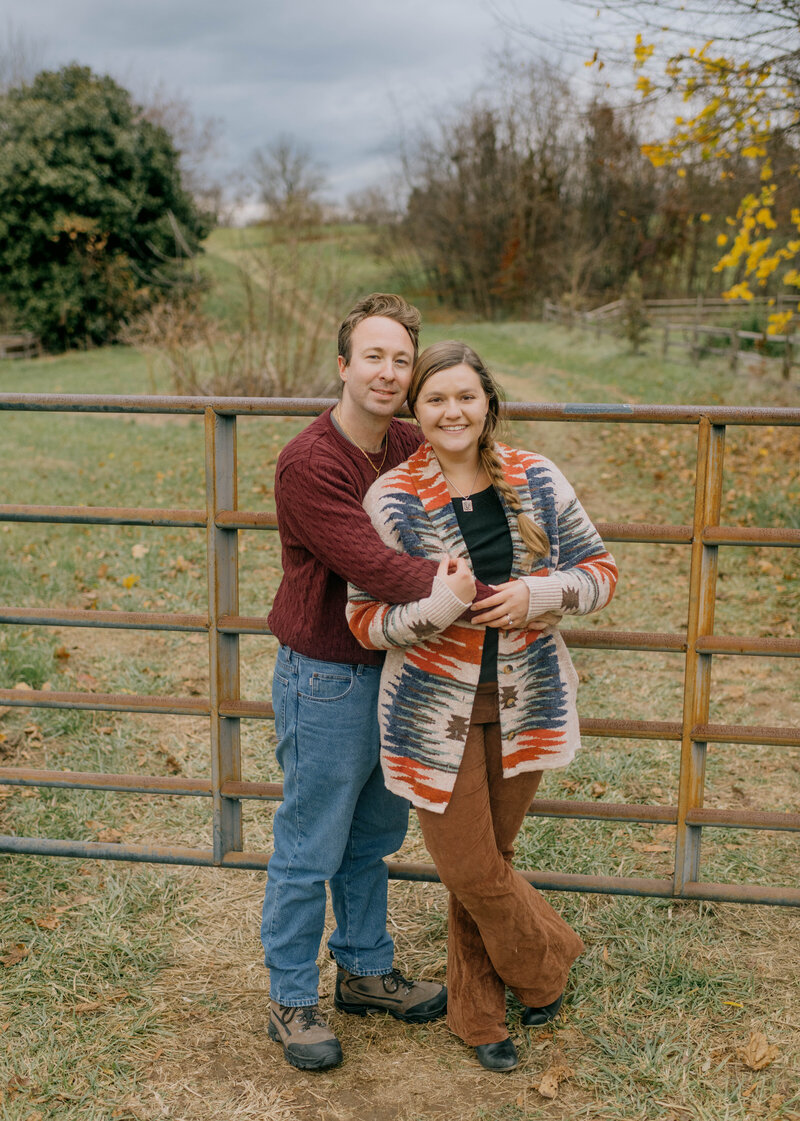 Husband and wife pose for photos in front of gate in Broadway.