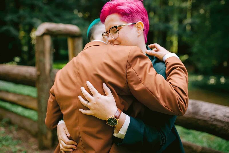 Lesbian wedding, two brides wearing suits hugging on their wedding day 