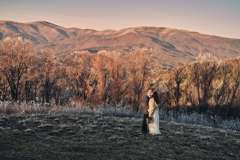Couple shares a kiss with snowy mountains in the background