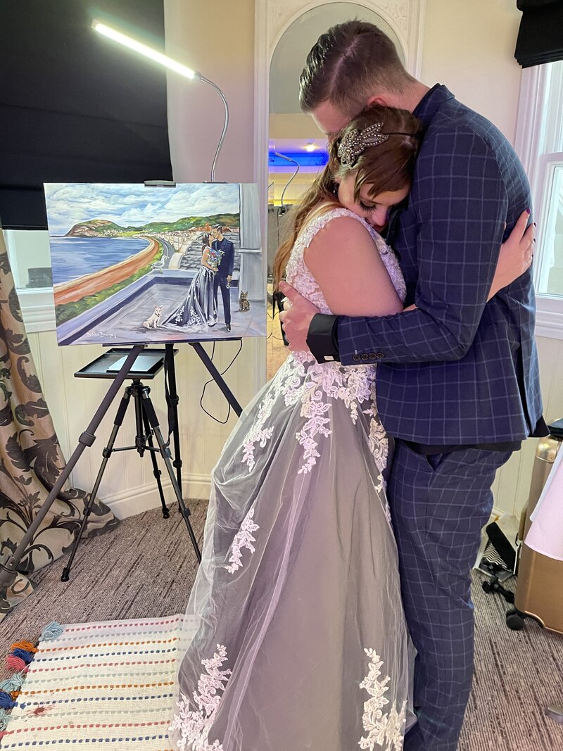 Kaleigh hugging her husband in front of their completed live wedding painting