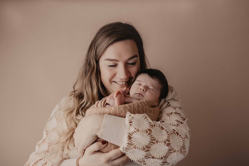 Een babymeisje tijdens de geposeerde newbornshoot door Evita Fotografie in de fotostudio in Zwartsluis. Roze achtergrond met haarband