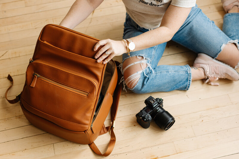 woman sitting on floor with camera, opening brown camera bag